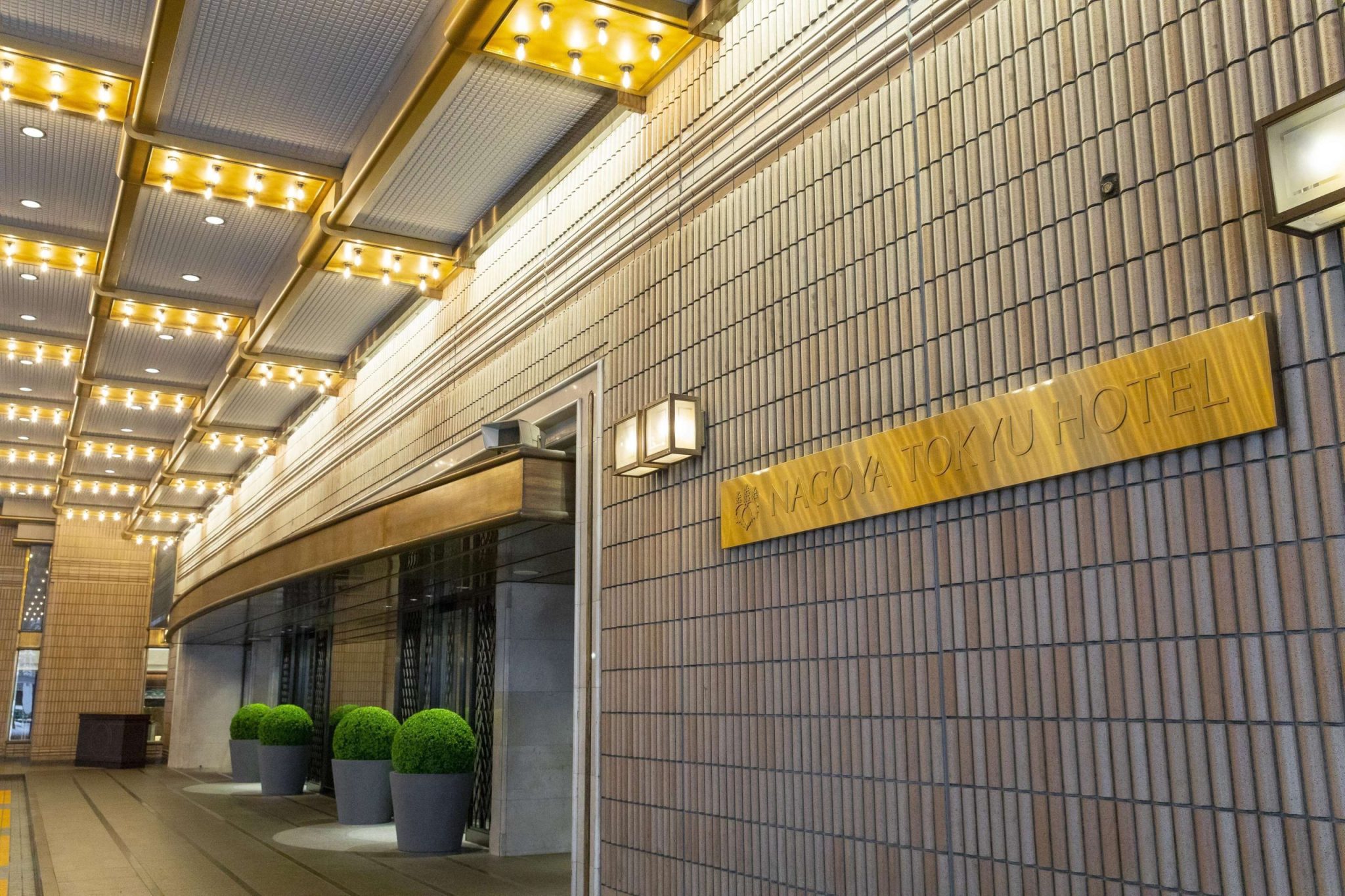 ‘NAGOYA TOKYU HOTEL’ 글자가 붙은 벽과 조명 캐노피가 있는 정문