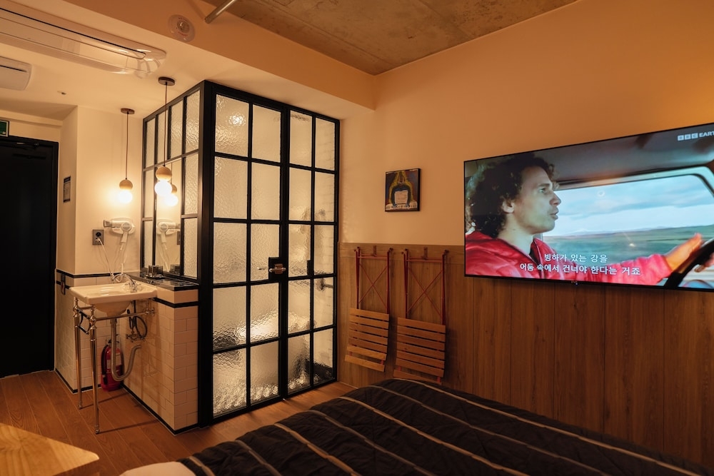 철제 격자 유리 욕실 칸막이와 벽걸이 TV가 있는 객실