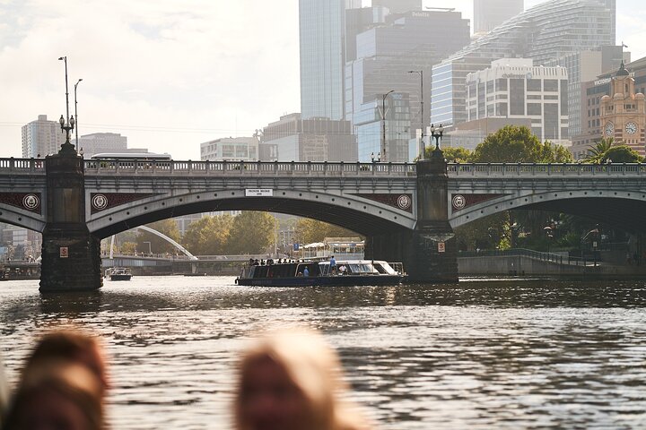 프린스 브리지 아래를 지나는 크루즈선. 다리 위에 ‘PRINCES BRIDGE’ 표지가 붙어 있고, 뒤로 도심 고층 빌딩이 이어진다
